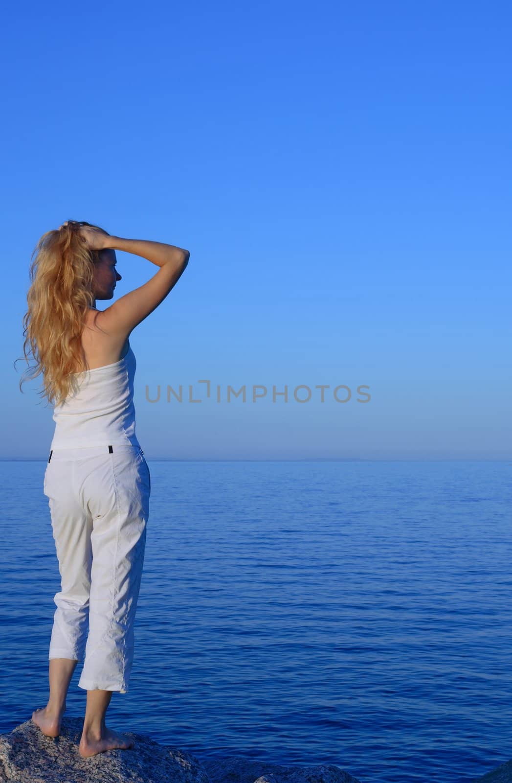 Beautiful young woman playing with her hair, looking at the sea.