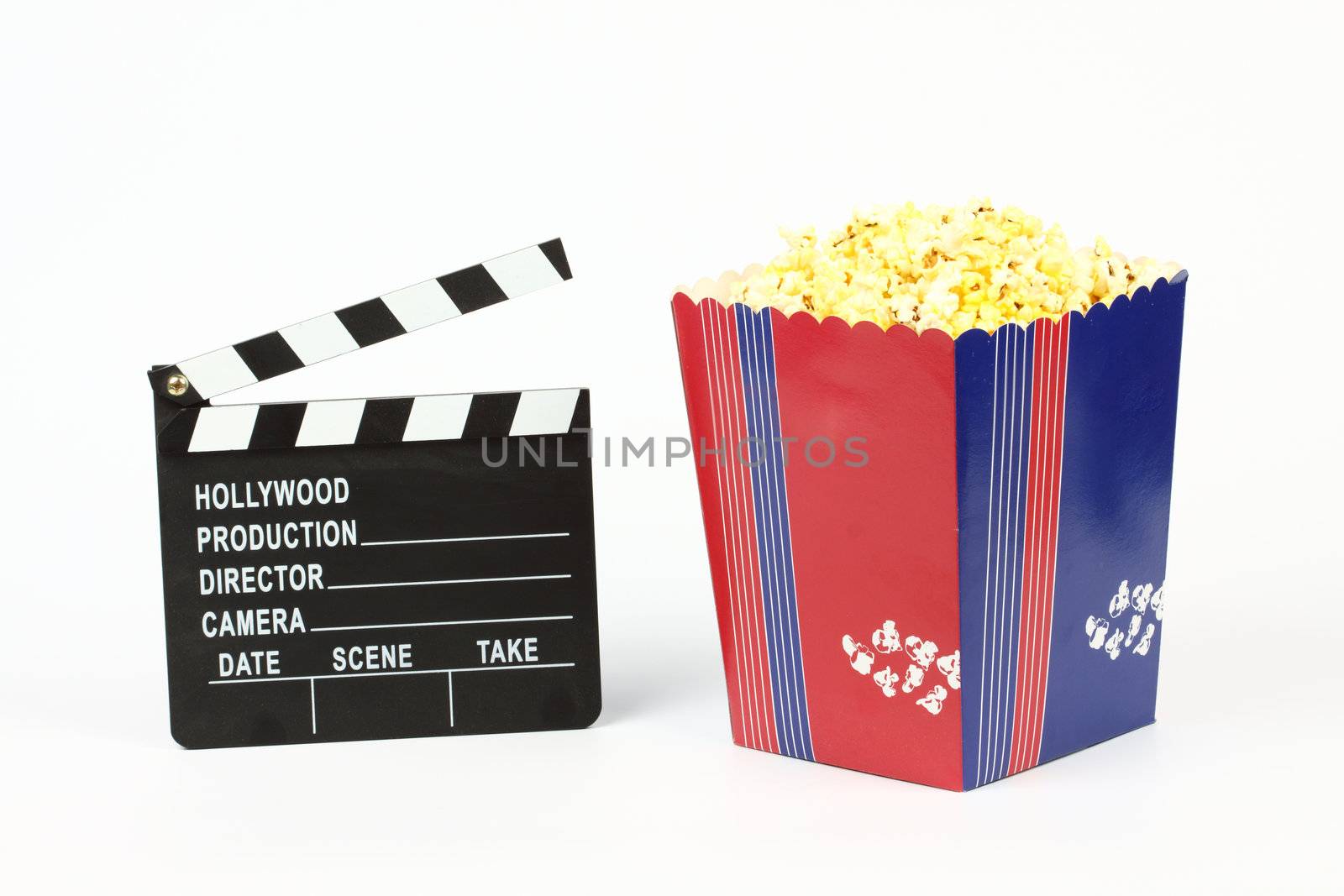 Movie clapper board and box of popcorn over white 