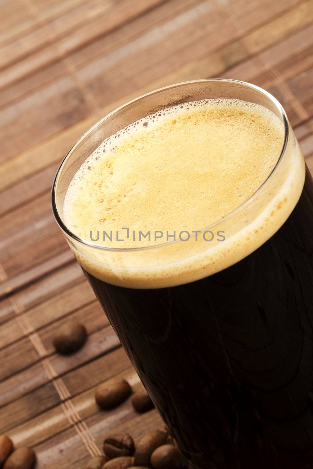 espresso in a diagonal glass with coffee beans on wooden background