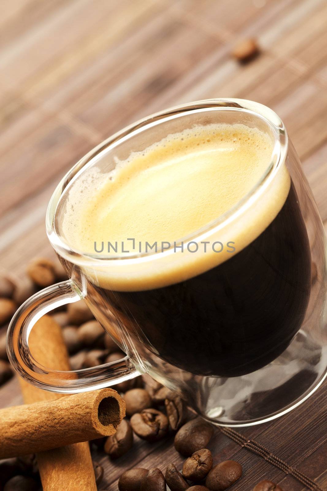 espresso diagonal with coffee beans and cinnamon sticks on wooden background