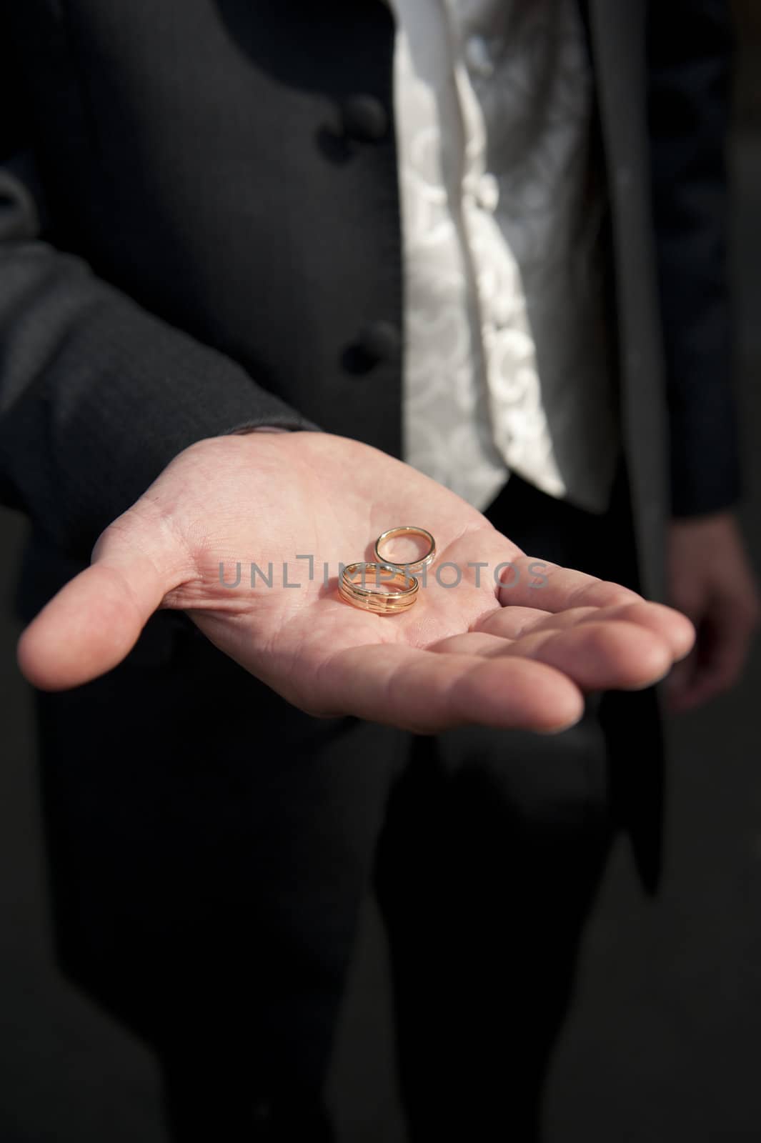 bridegroom holding two gold wedding rings in palm of hand by paddythegolfer