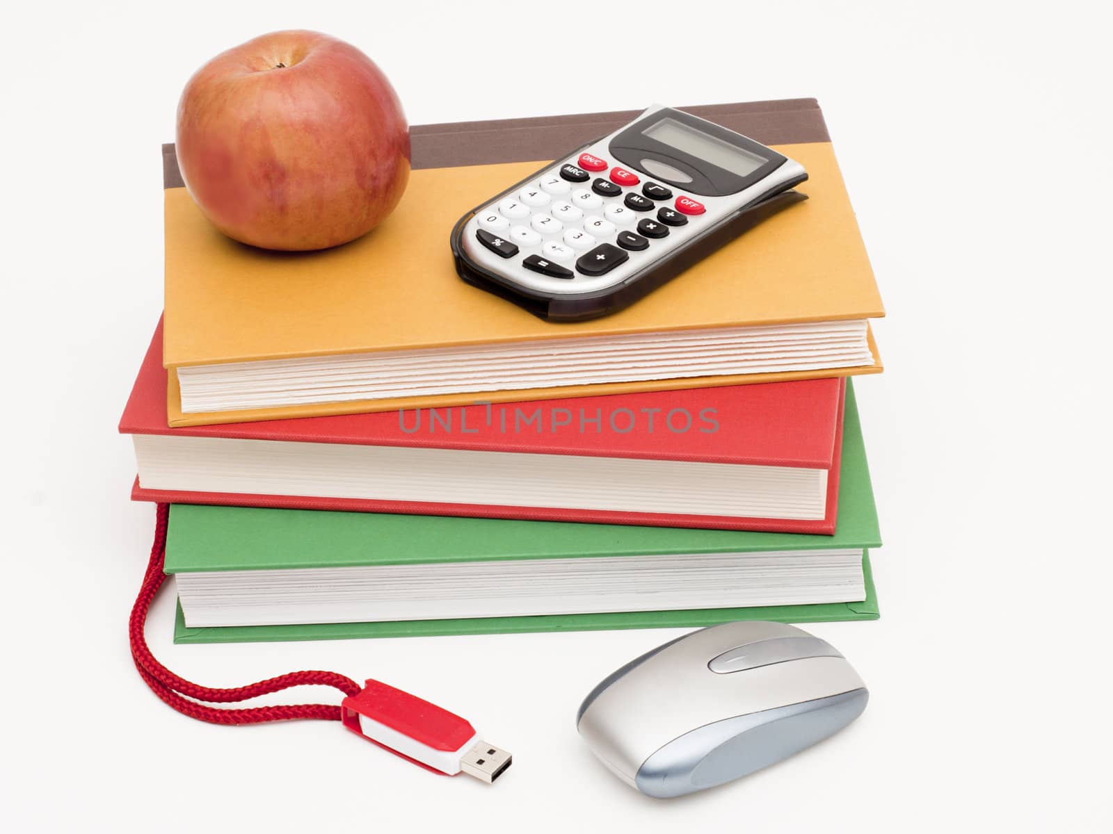 Back-to-school collection of hardback textbooks, calculator, thumb drive and mouse with an apple for the teacher on top. Isolated on white.