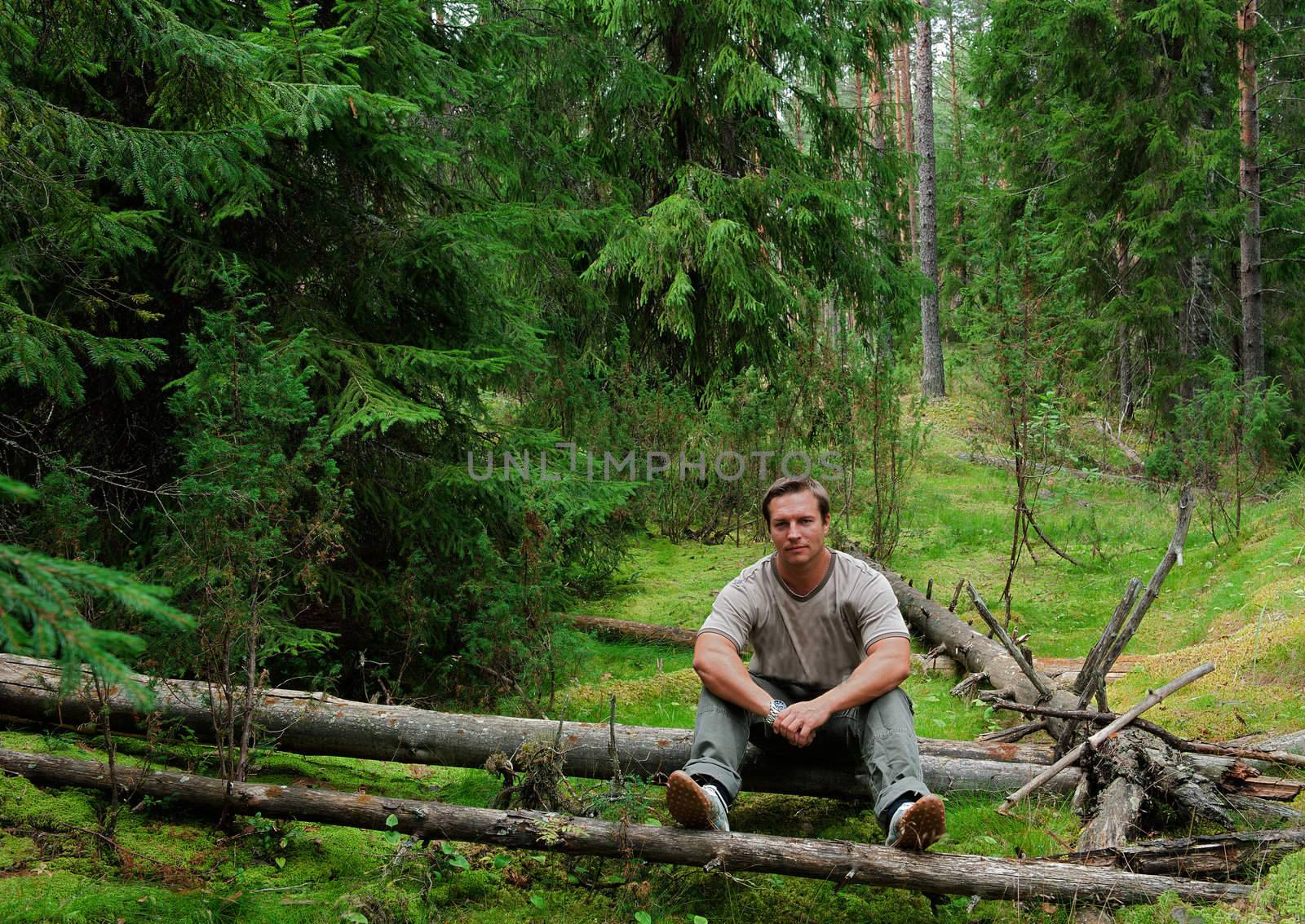The man in  forest sits on a log