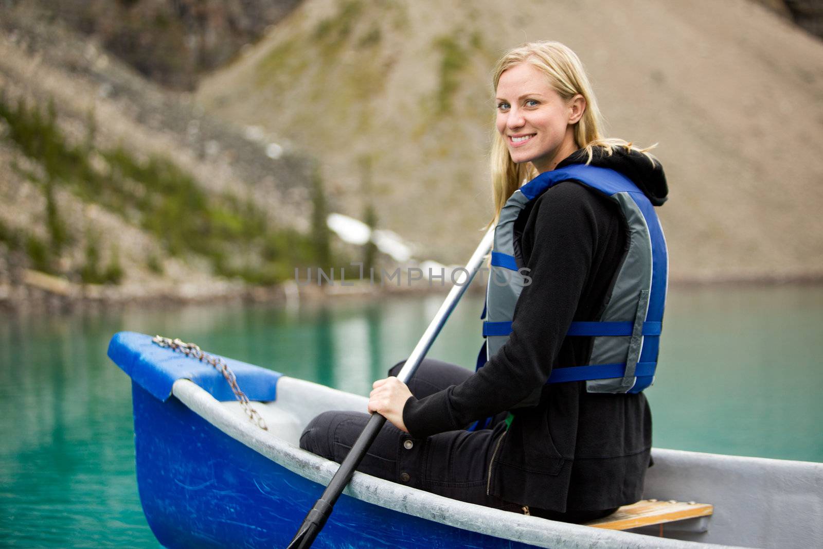 A portrait of a happy woman canoeing on a glacial lake
