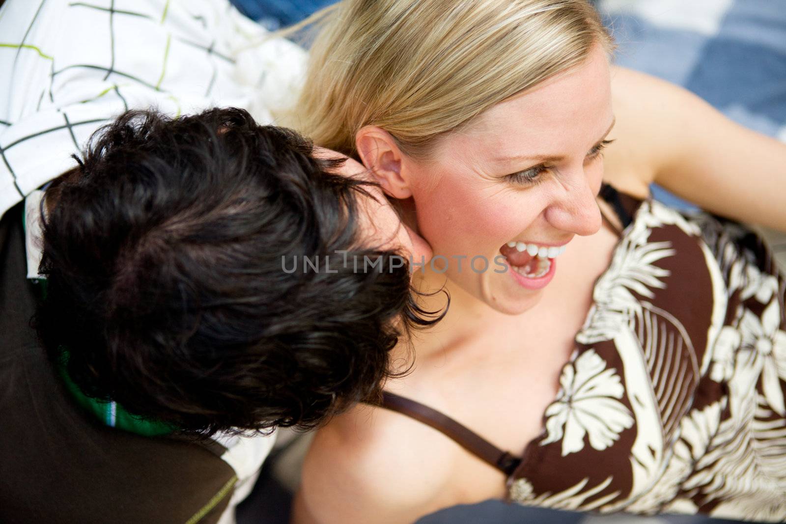 A man kissing a woman on the neck and a woman smiling