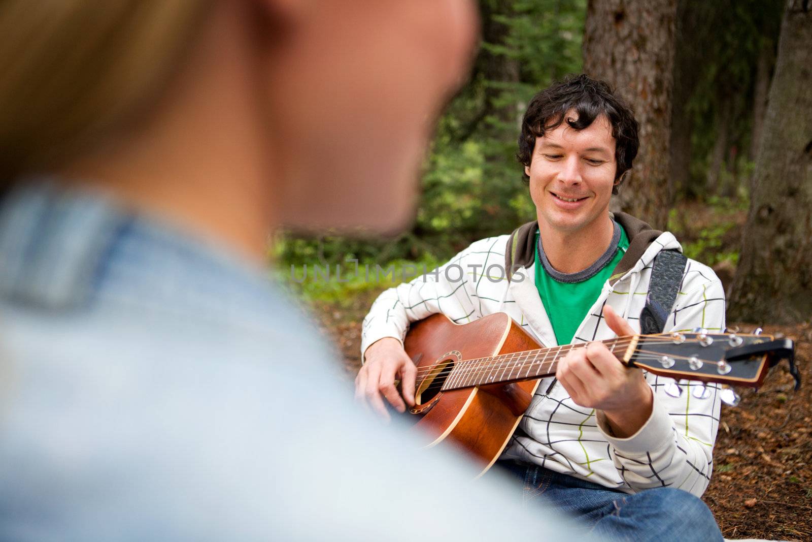 Man Playing Guitar for Woman by leaf