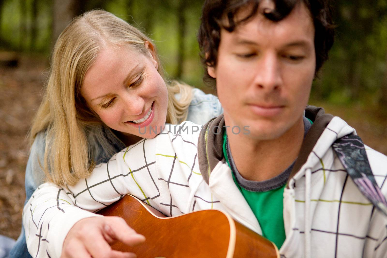 A couple enjoying themselves outdoors with a guitar, focus on woman