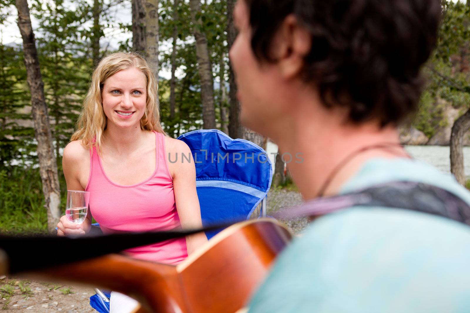 A man playing a guitar outdoors for a girl