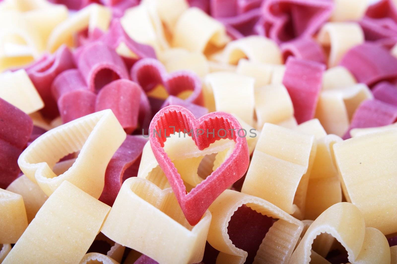 Red and yellow pasta hearts filling frame. 