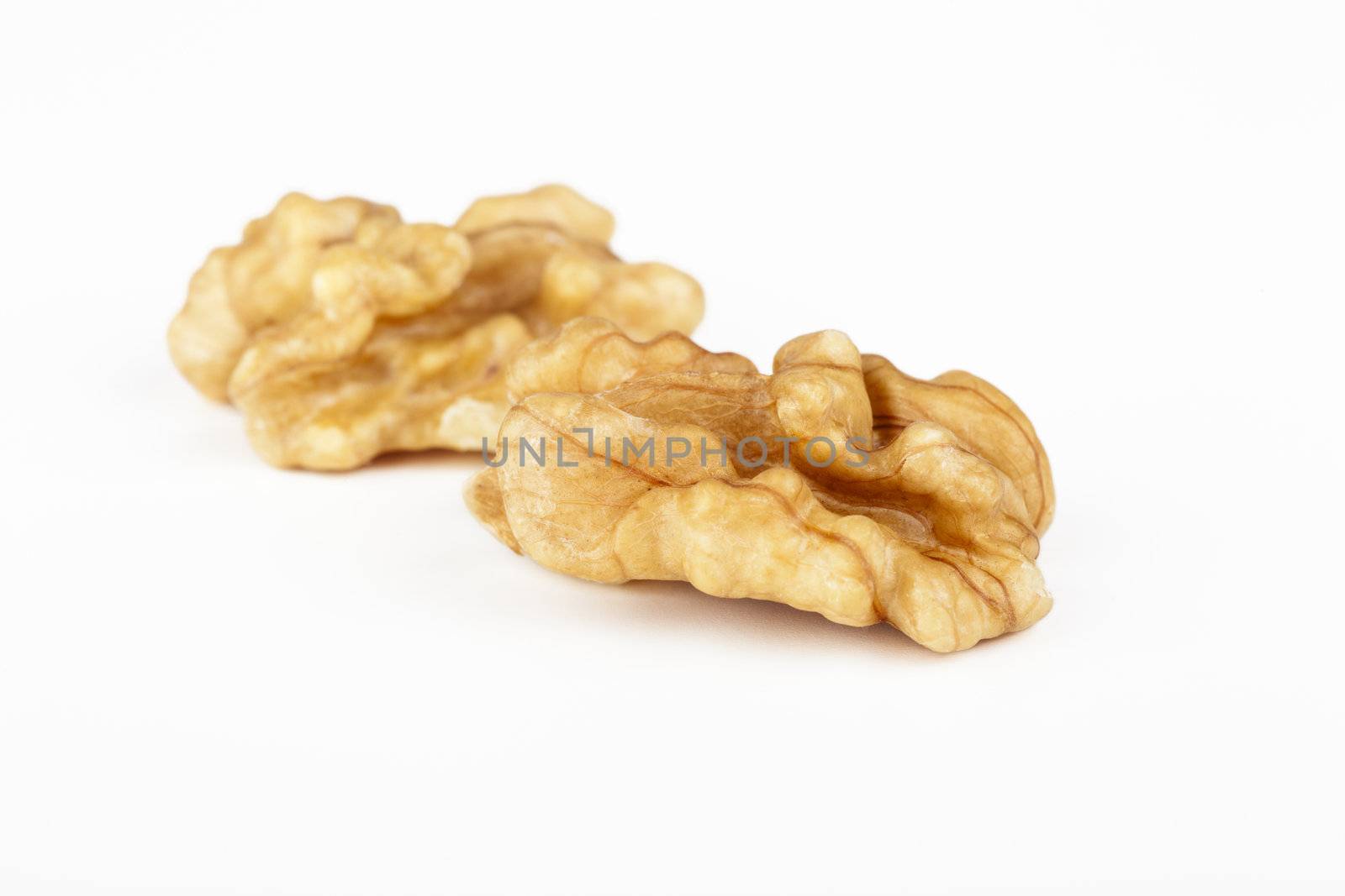 Two raw shelled walnut halves on white background