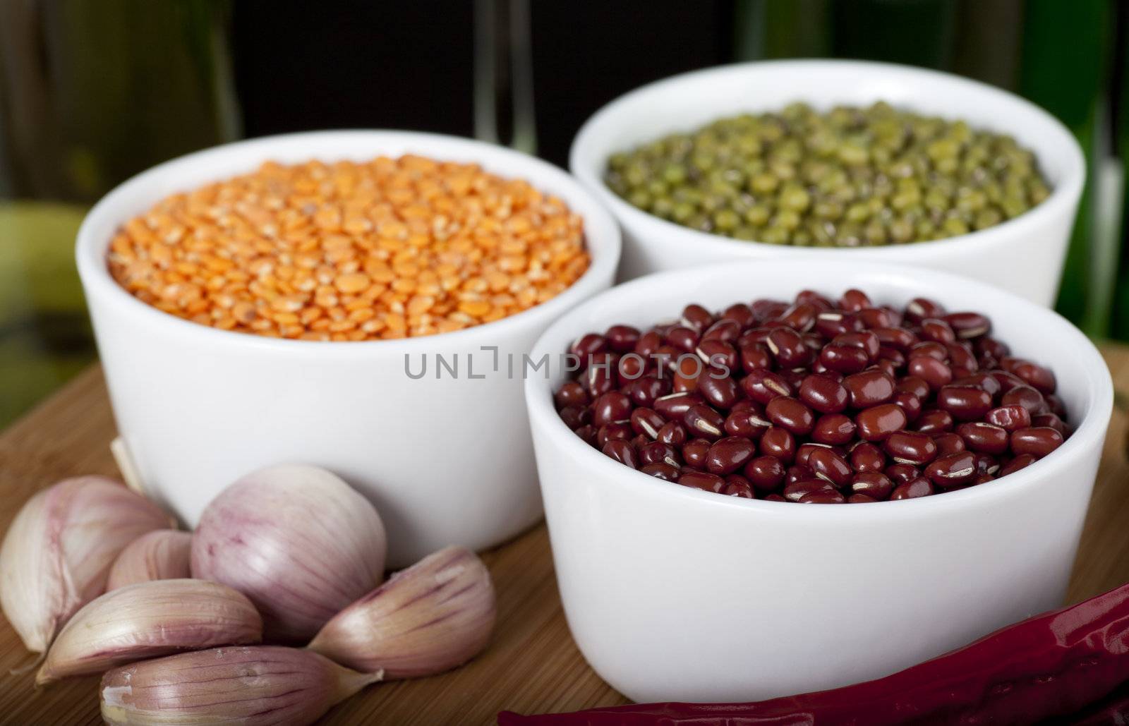 Three types of beans: lentils, mung and azuki, with cloves of garlic.