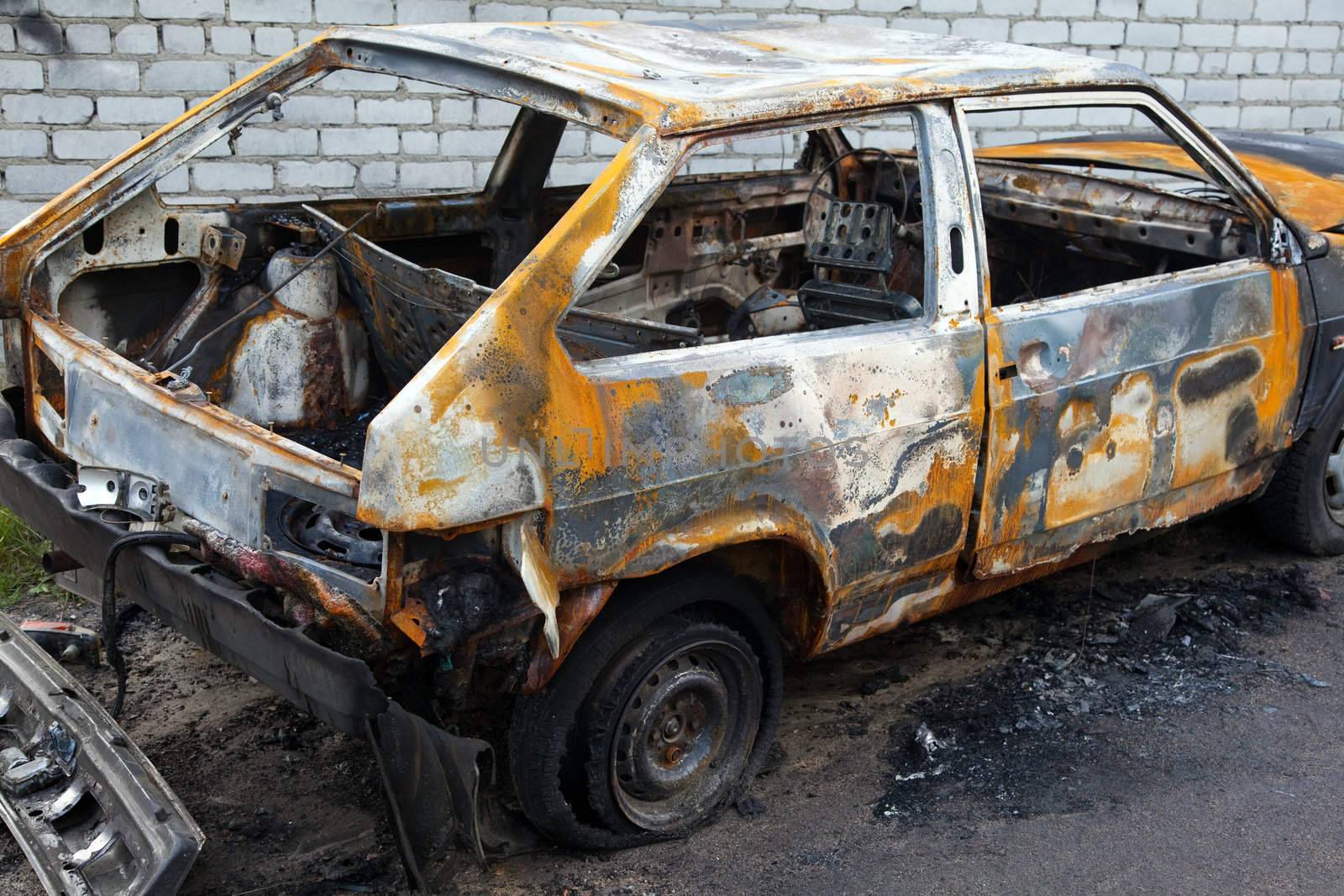 
Burnt cars at the front of a brick wall
