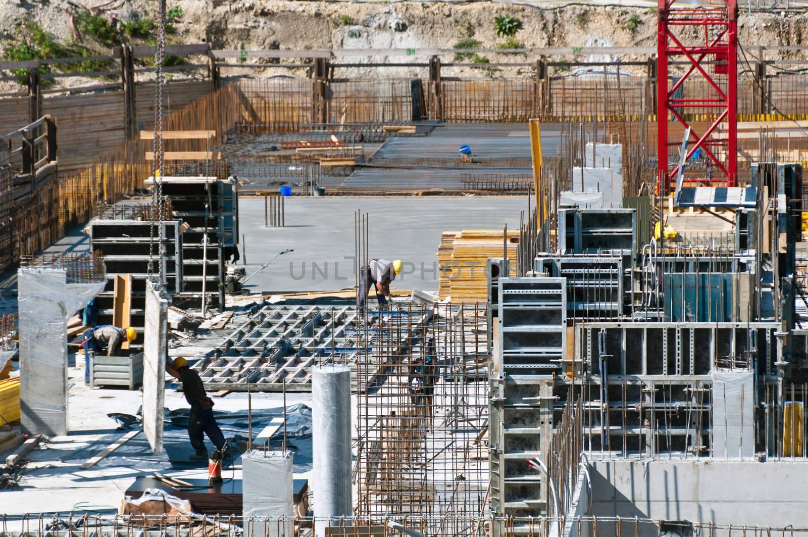 Detail of construction site with workers, scaffolding, crane and assets