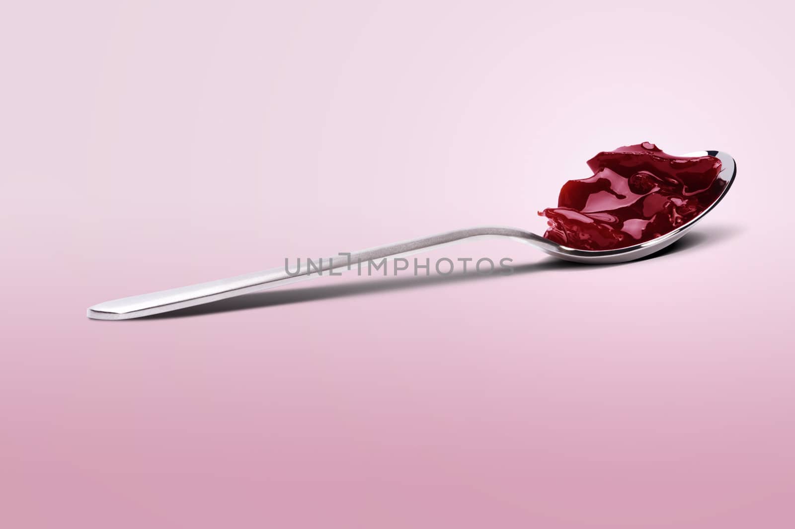 spoon with cherry jam over pink gradient 