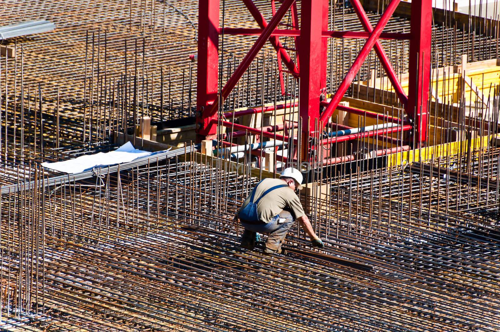 Detail of construction engineer with plan on site with steel and crane
