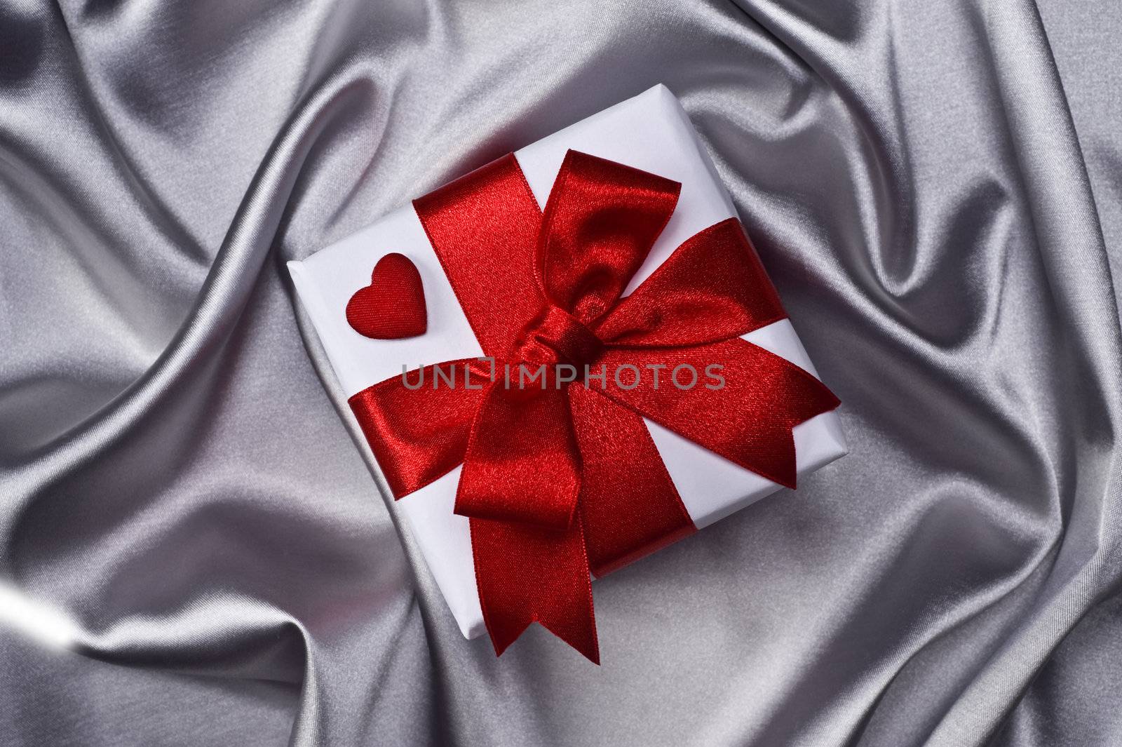 gift with decorative red ribbon on silver background