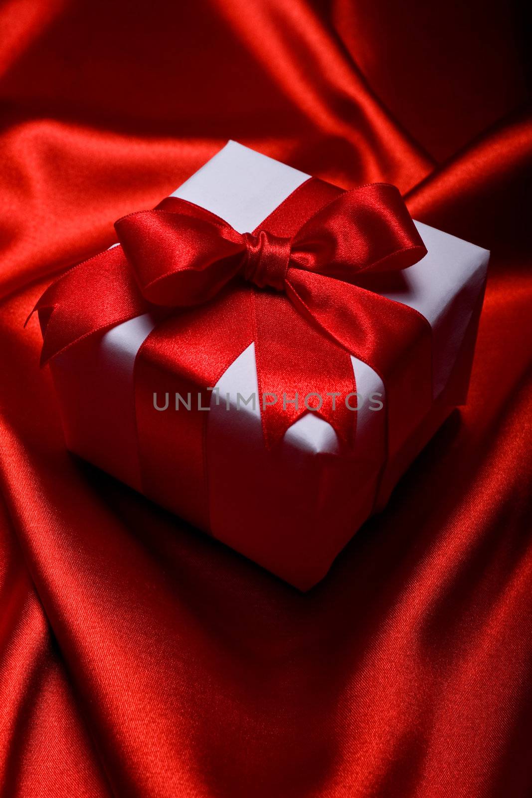 gift with decorative red ribbon on red silk background