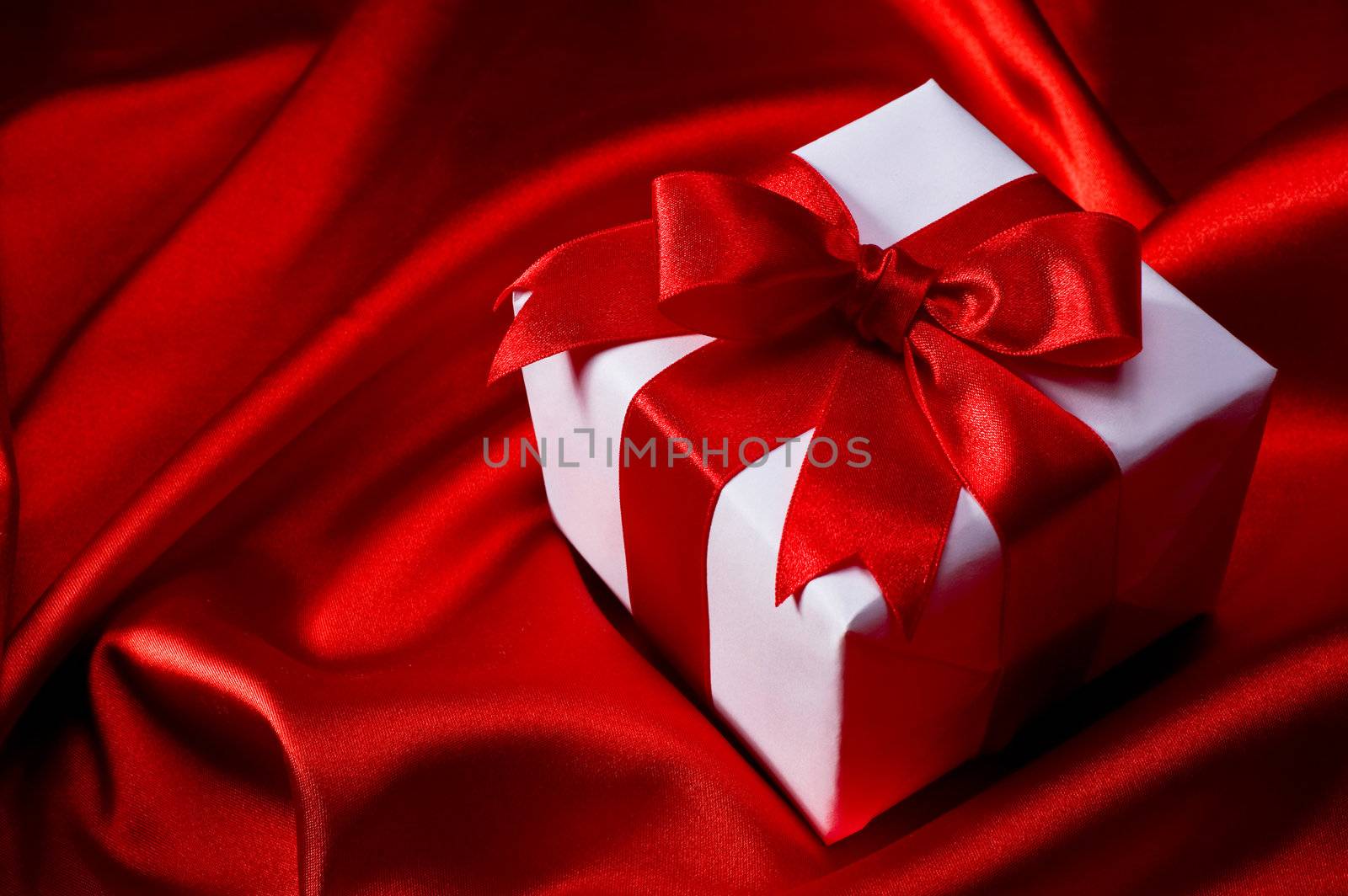 gift with decorative red ribbon on red silk background