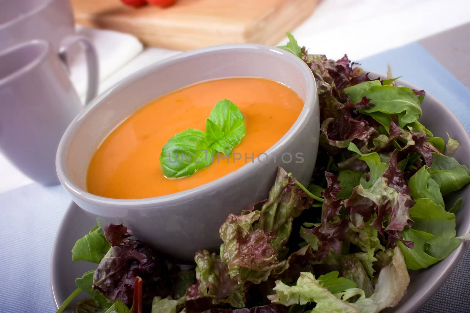 Creamy tomato soup with salad greens and garnished with basil leaves