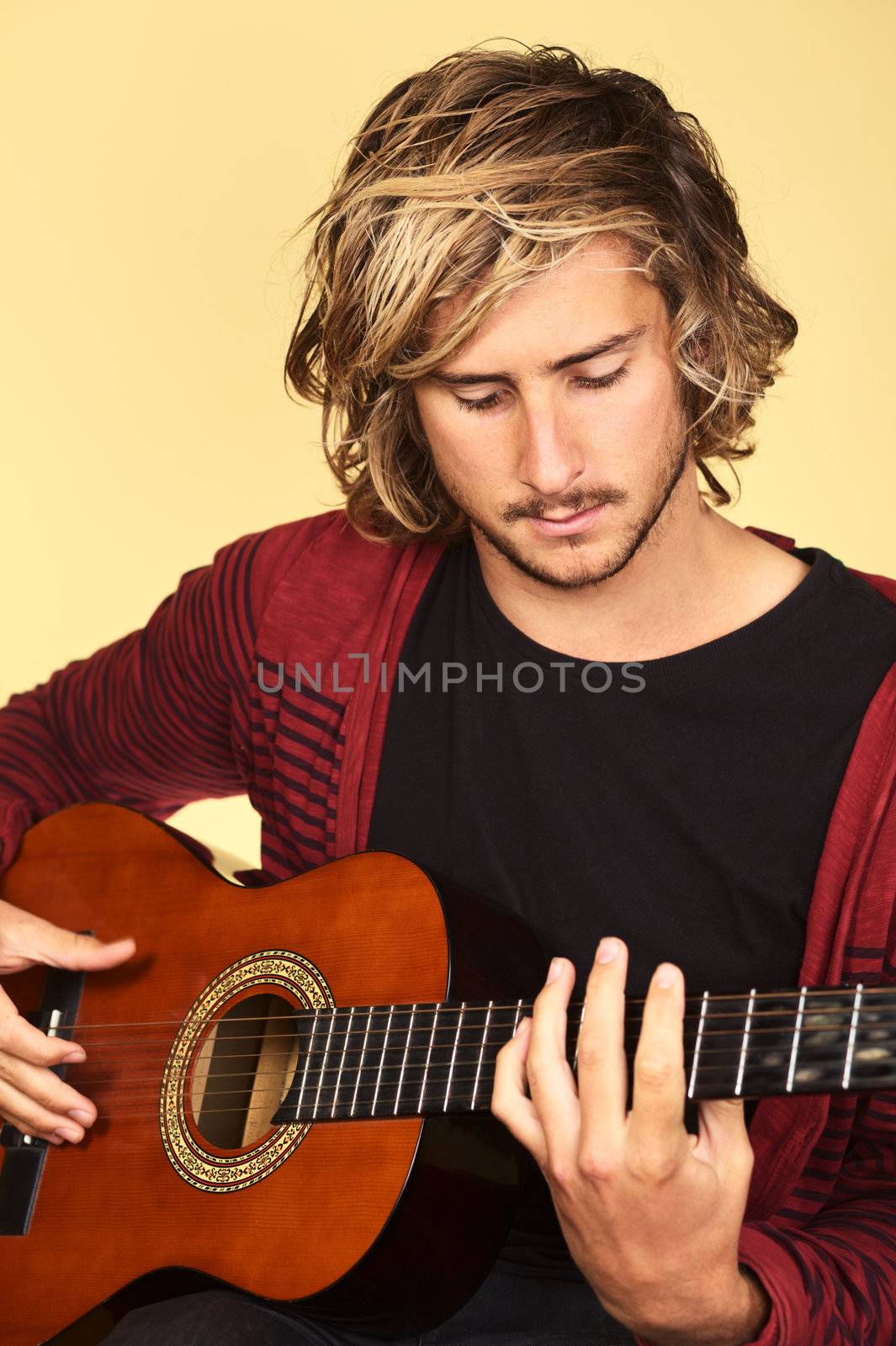 Young handsome Caucasian man playing the guitar (Selective Focus, Focus on the eyes)