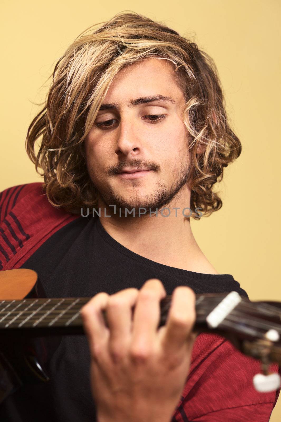 Young handsome Caucasian man playing the guitar (Selective Focus, Focus on the left eye)
