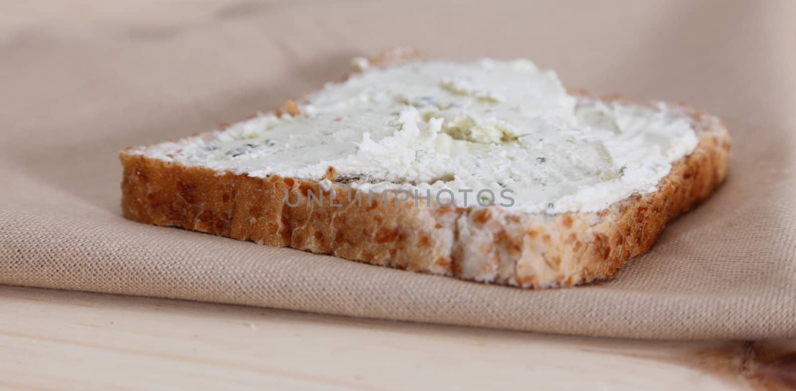 Bread with cheese on a piece of cloth on a wooden table.