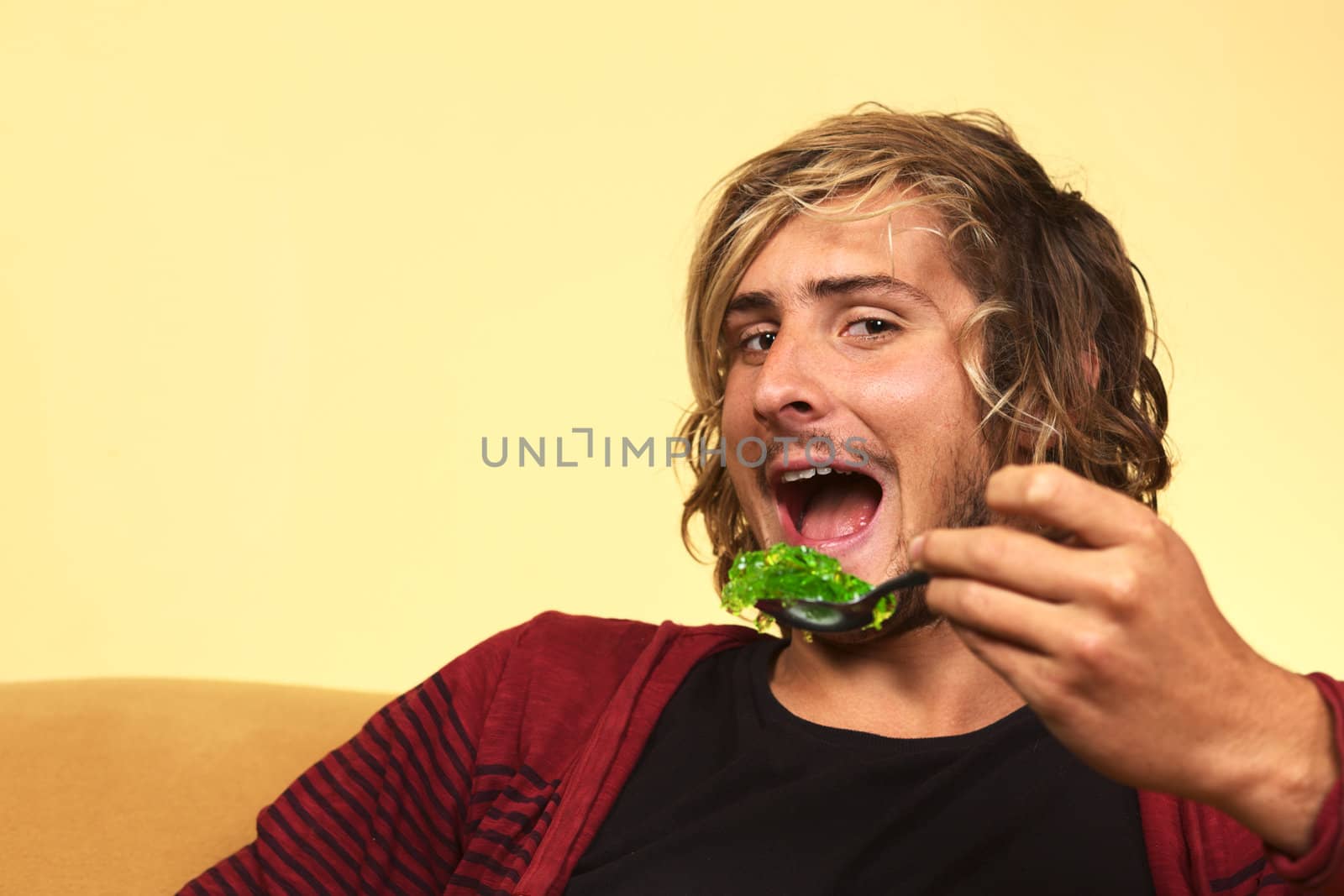 Young handsome man enjoying green jelly (Selective Focus, Focus on the left eye)