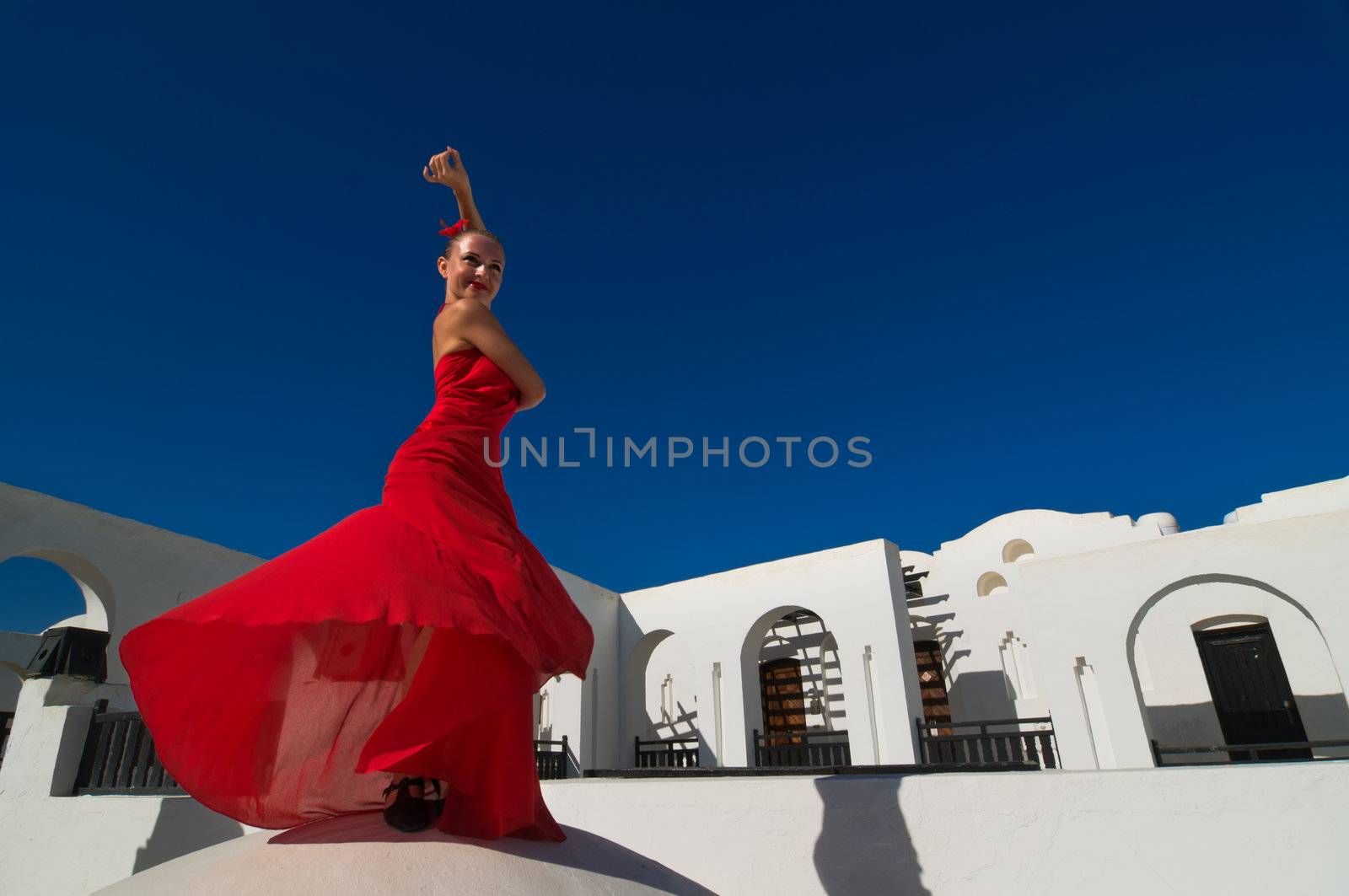 Attractive flamenco dancer wearing traditional red dress with flower in her hair