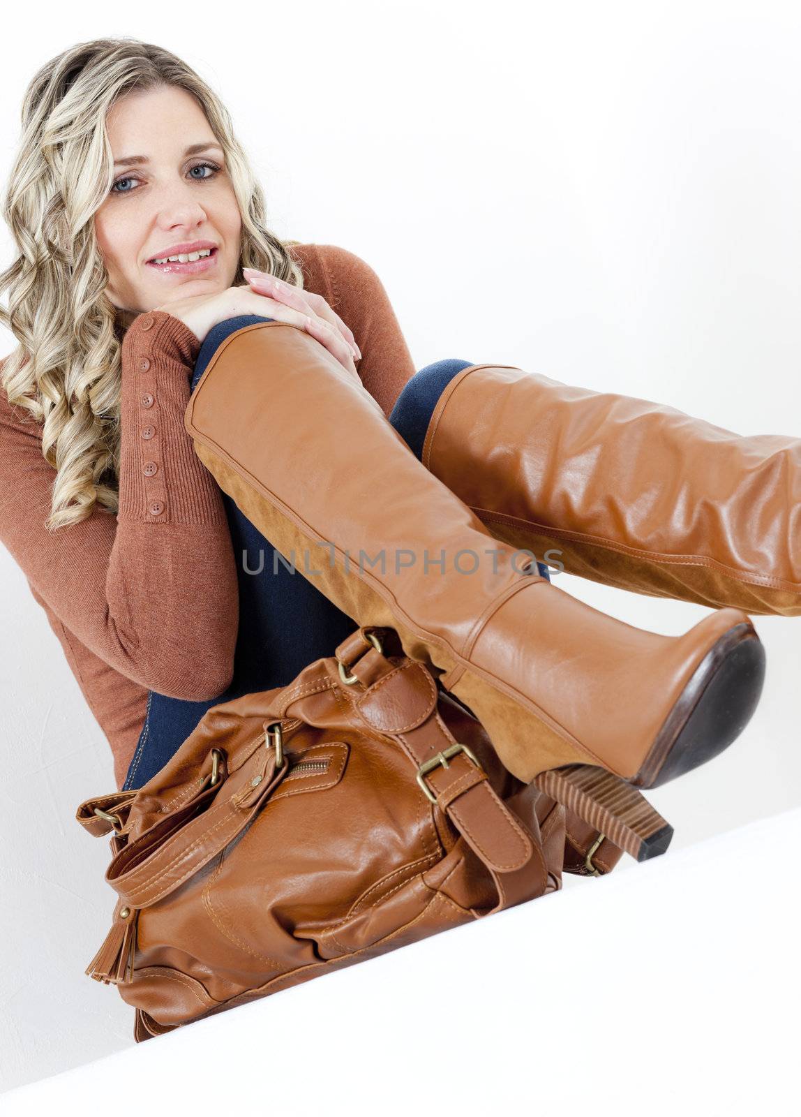 portrait of sitting woman wearing fashionable brown boots with a handbag