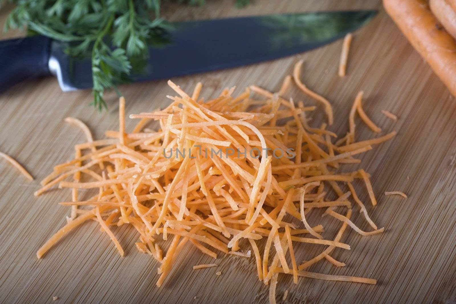 Finely shredded carrots on cutting board with knife.  