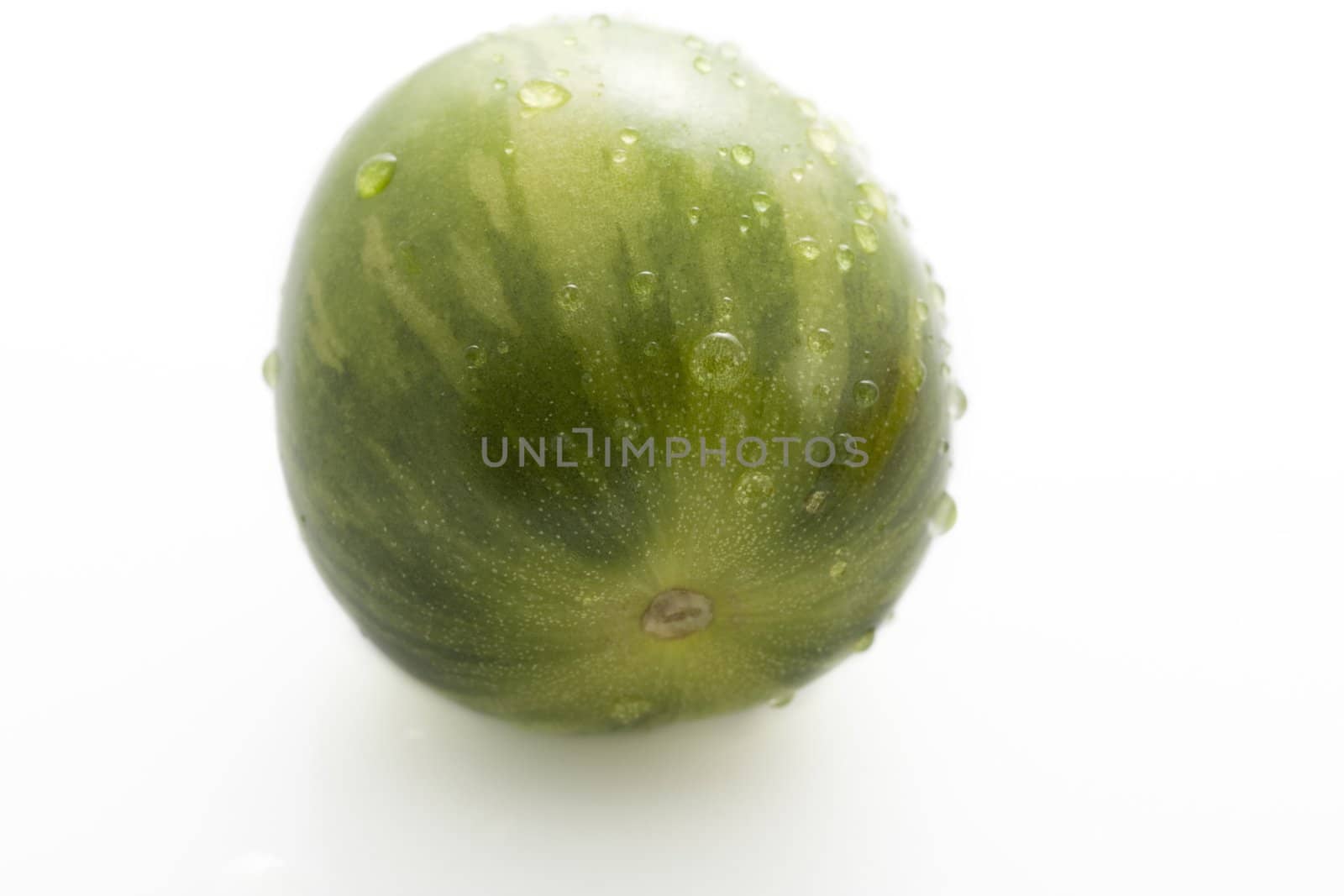 Close up of wild green tomato covered in water drops and isolated on white.