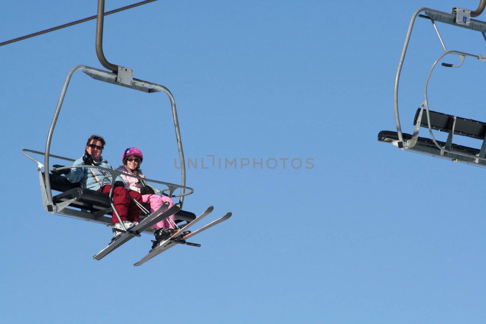 Two women riding on the ski lift on holiday.
