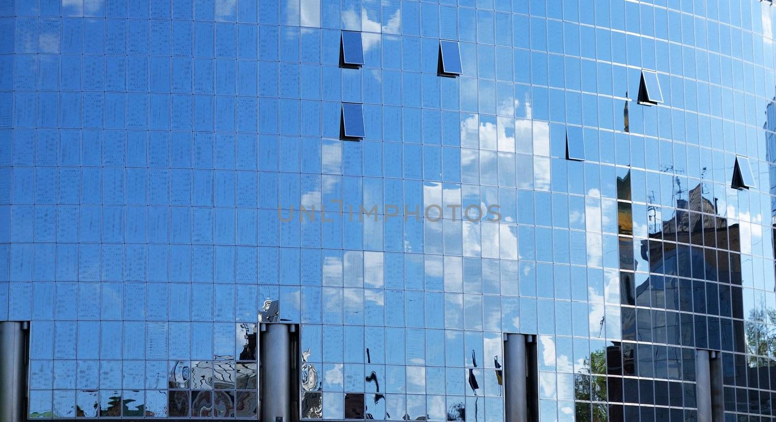 a mirror reflection of sky and clouds is in the windows of building