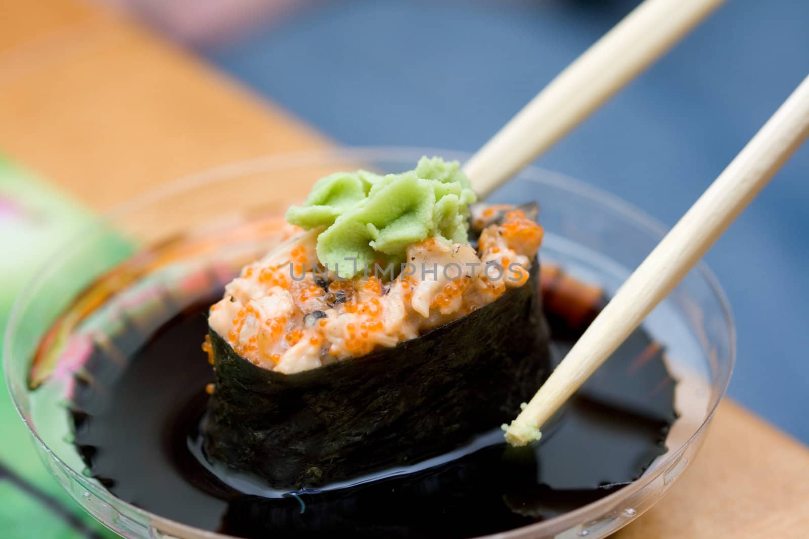 taking sushi with chicken and wasabi from plastic saucer with chopsticks