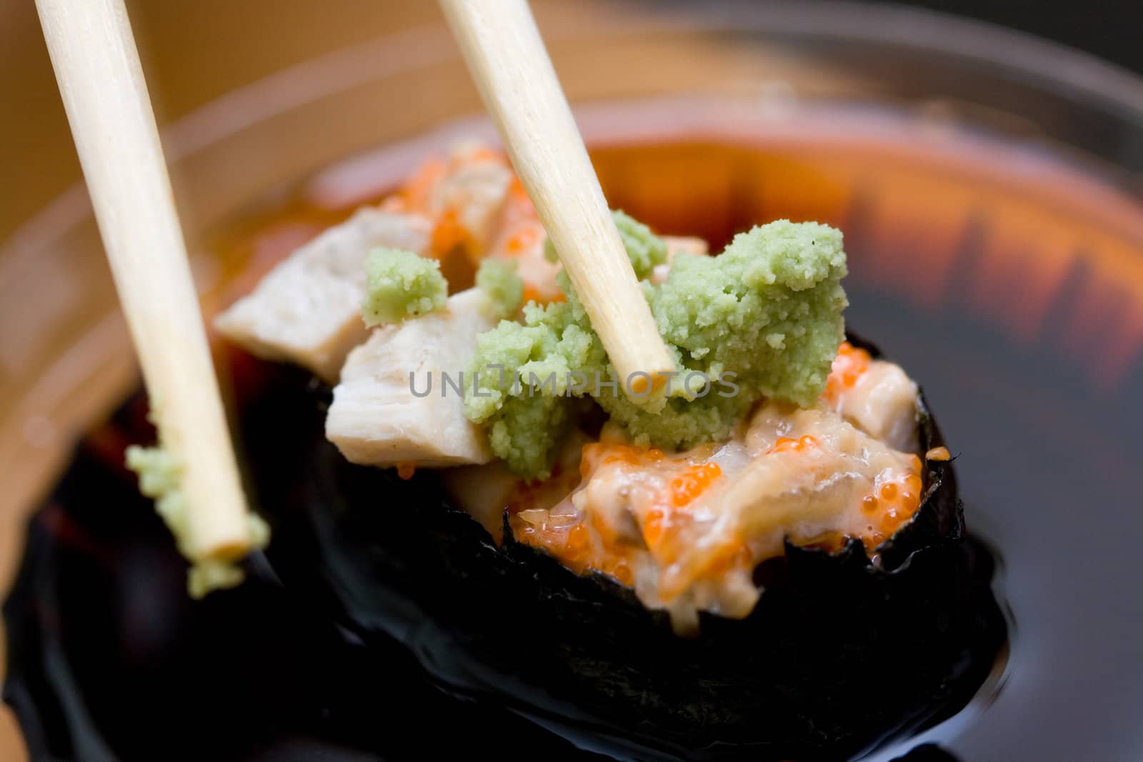 taking sushi with chicken and wasabi from plastic saucer with chopsticks