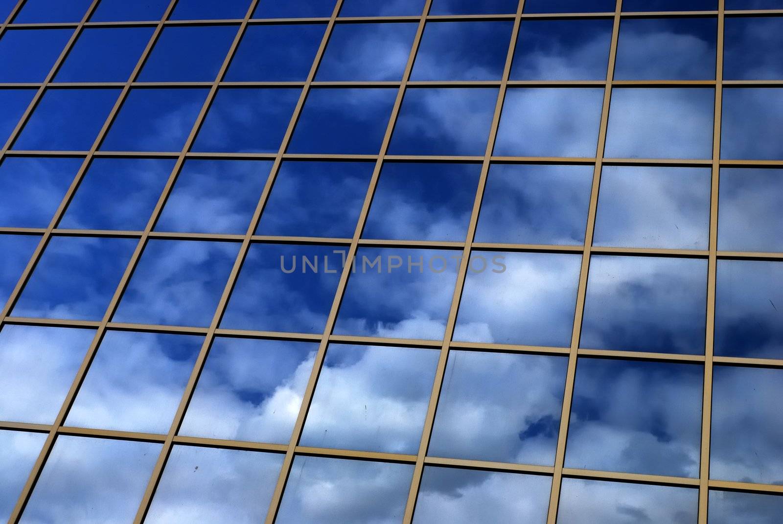a mirror reflection of sky and clouds is in the windows of building
