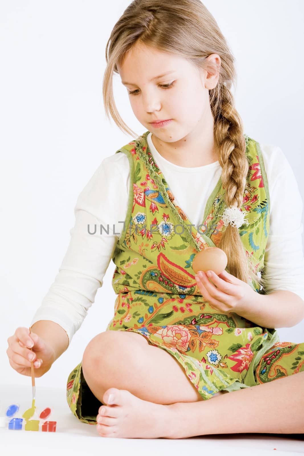 Studio portrait of a young blond girl who is painting eggs for easter