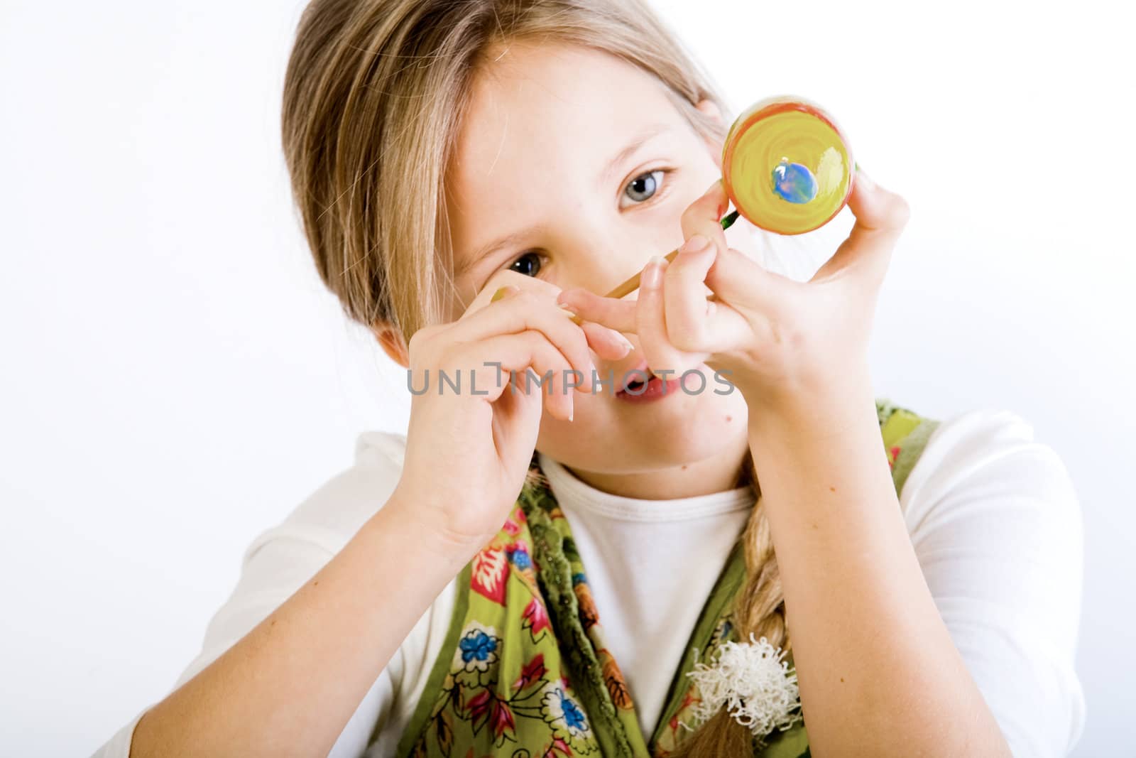 Studio portrait of a young blond girl who is painting eggs for easter