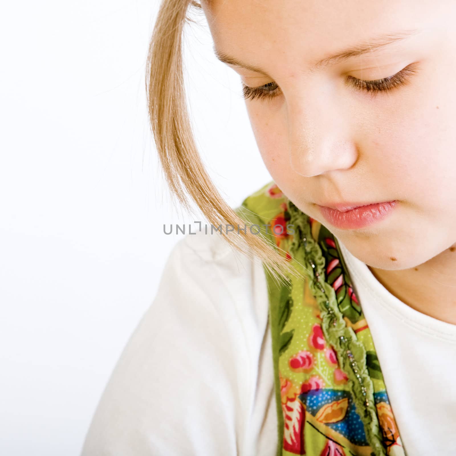 Studio head shot of a beautiful blond little girl in white shirt and green dress looking dreamy