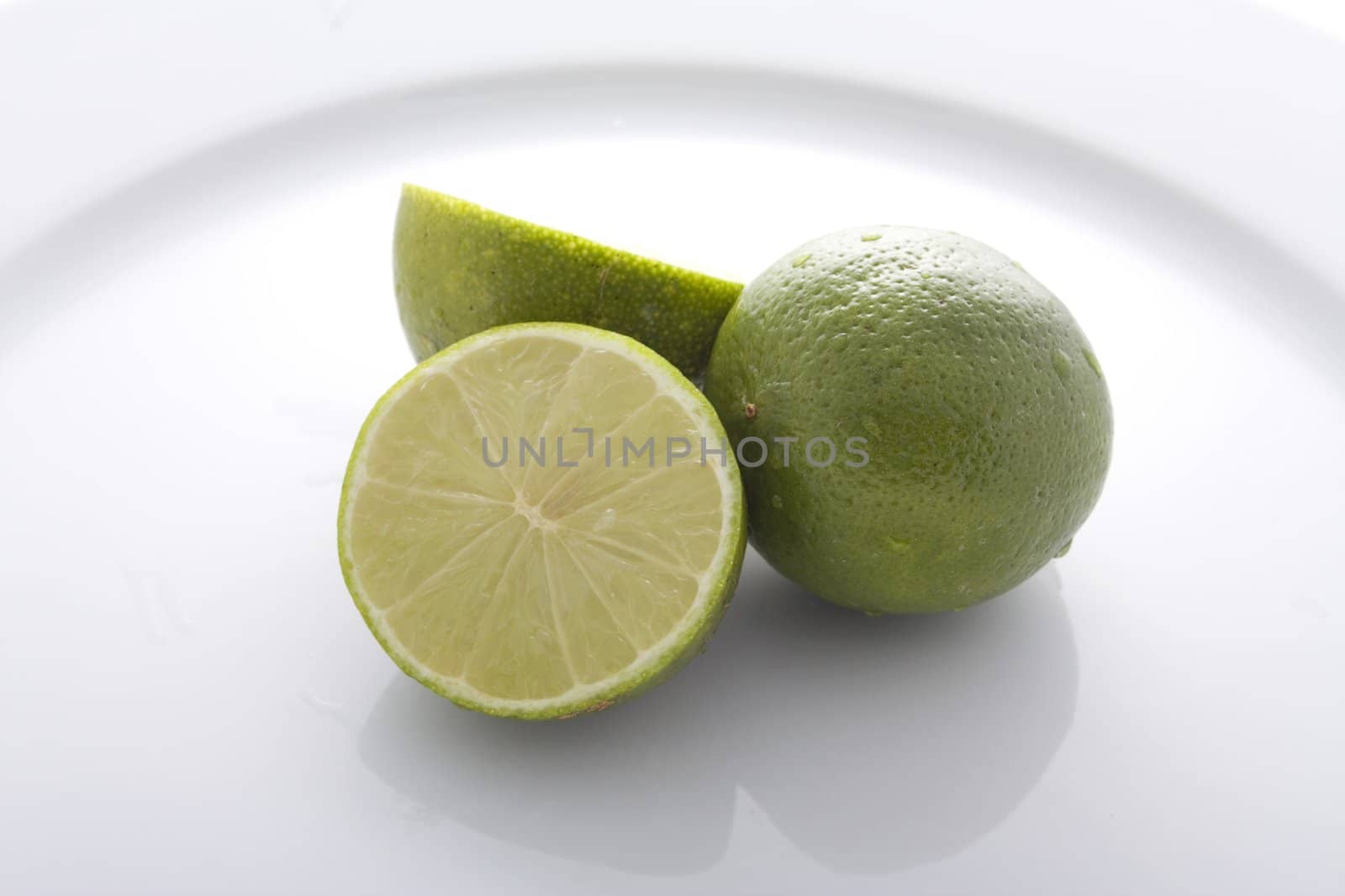 Cut lime and whole lime on white plate