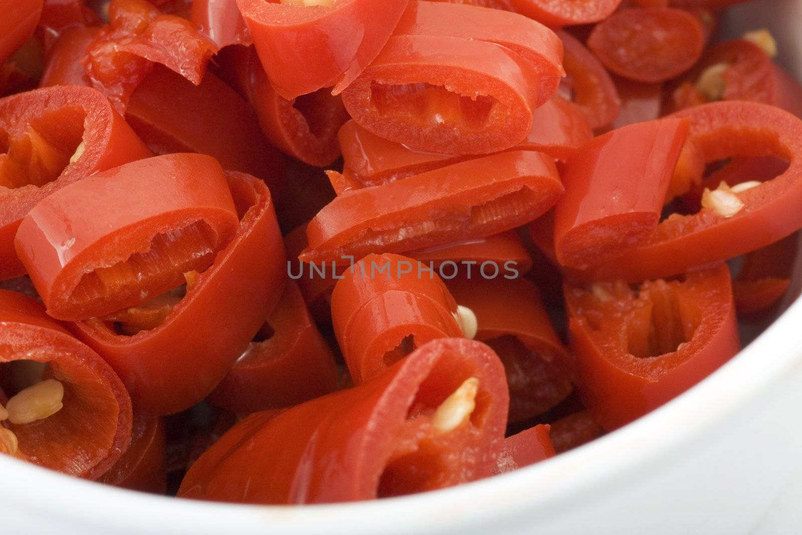 Close up of sliced hot peppers in a white bowl.  