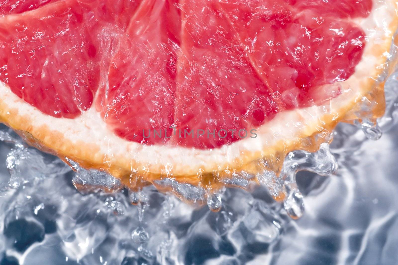 Grapefruit under running water, with water running over sides.
