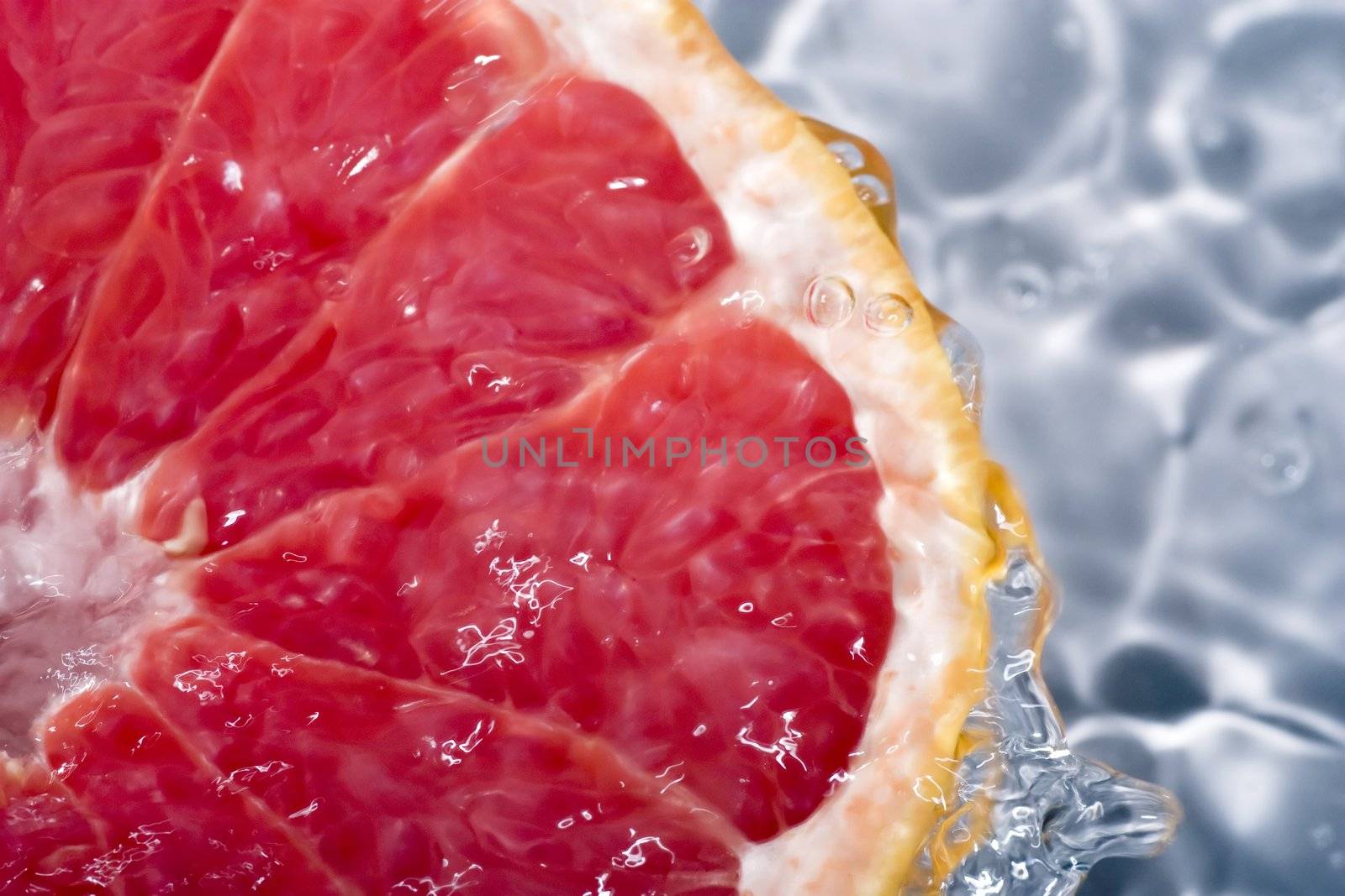 Grapefruit under running water, with water running over sides.