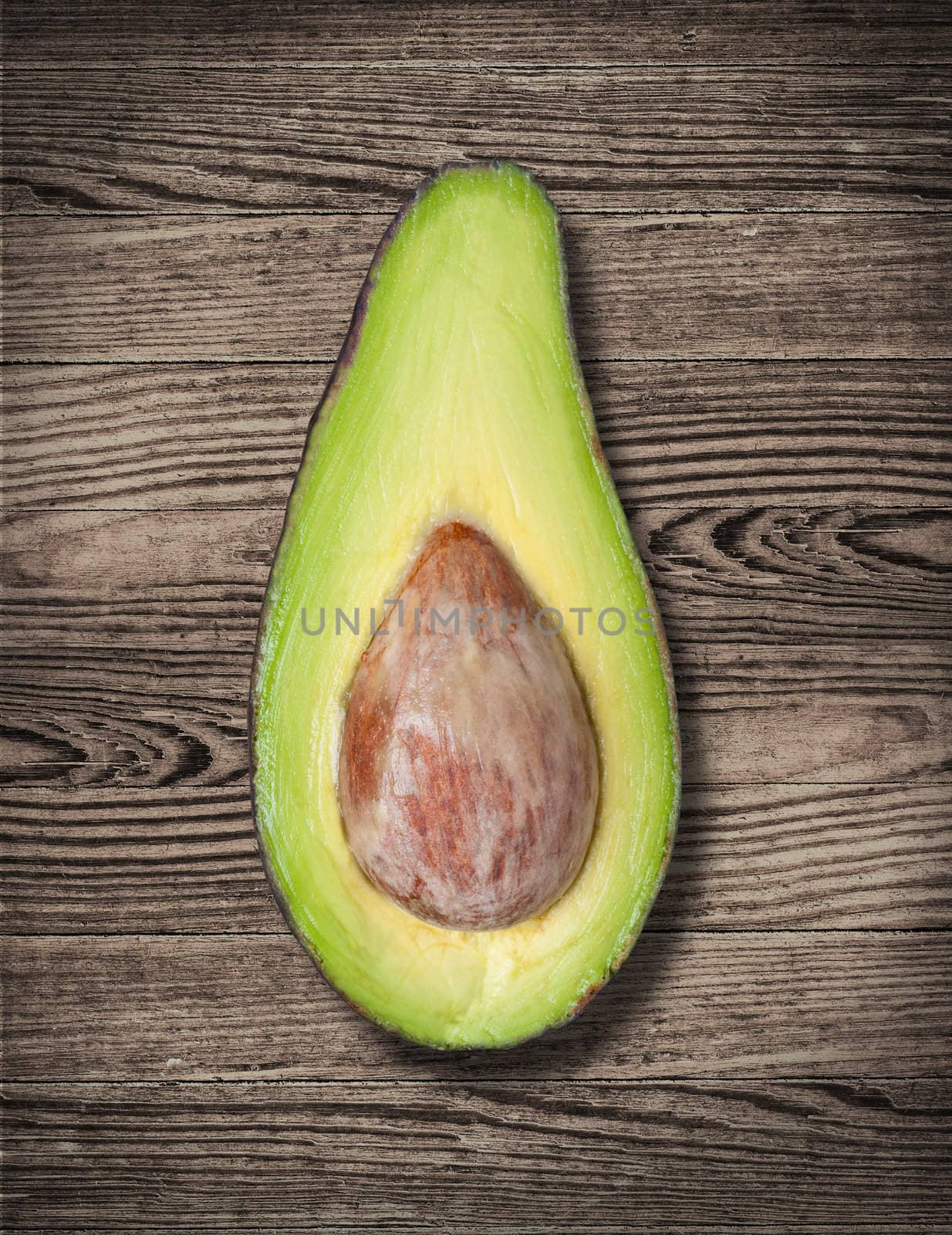 Avocado cut on wooden table, close up.