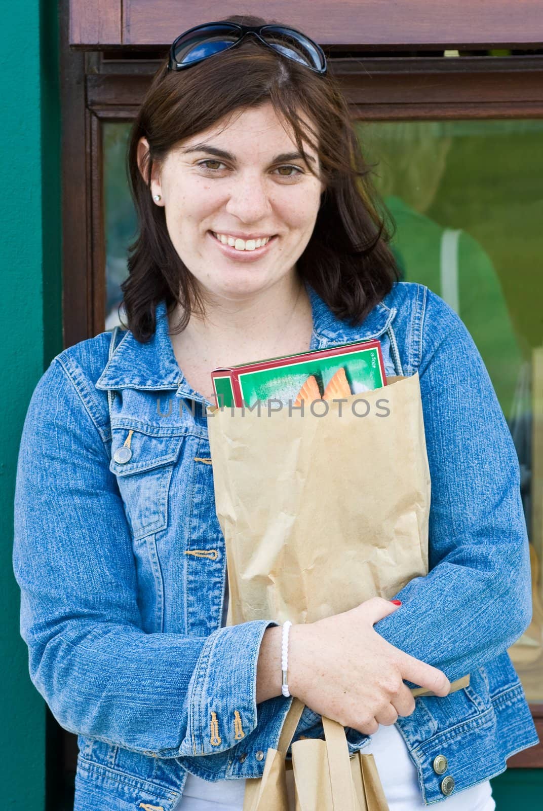 An attractive young lady standing outside a store. She is holding a package that she just purchased.