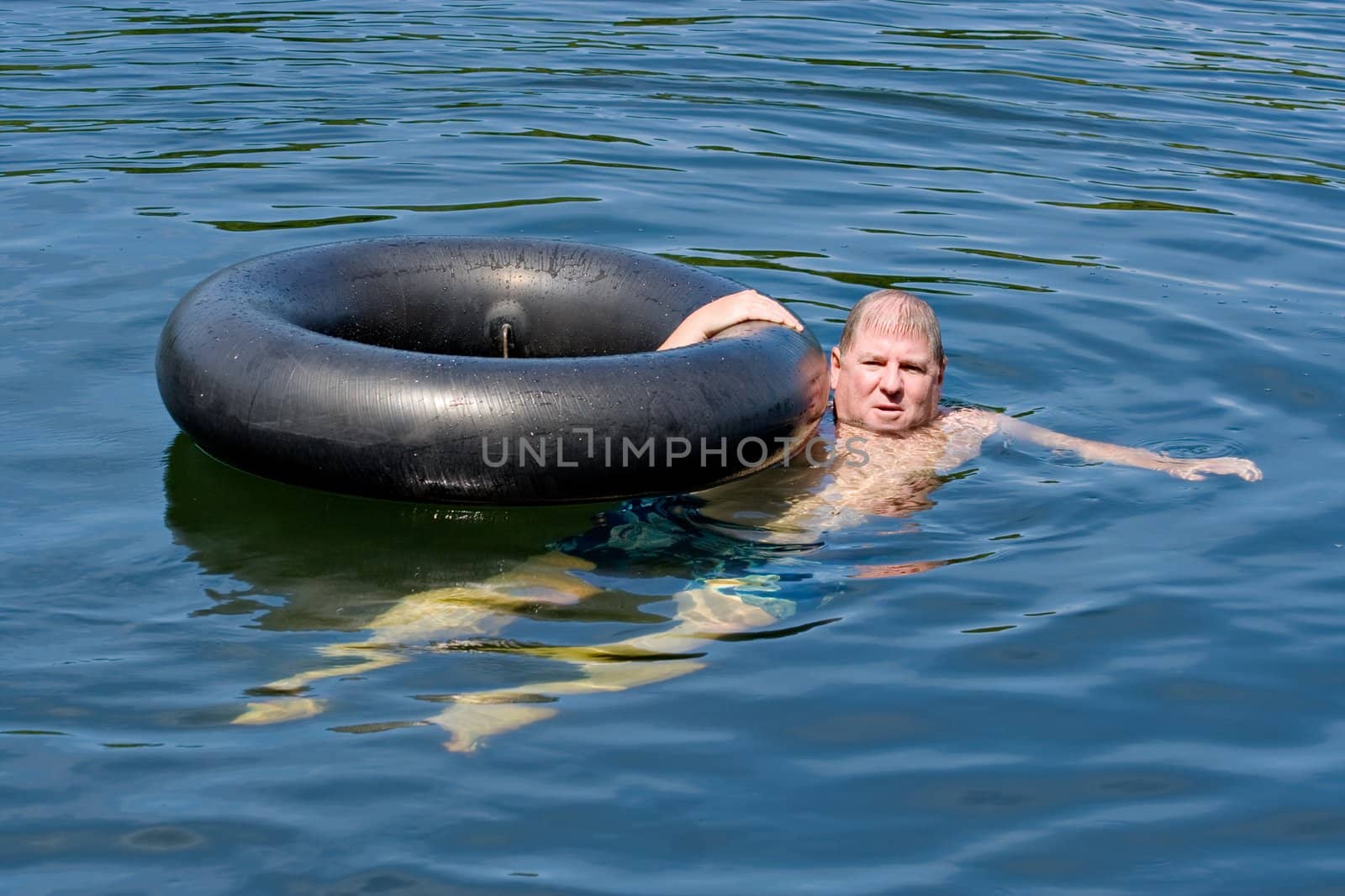 A man in water floating with an inner tube