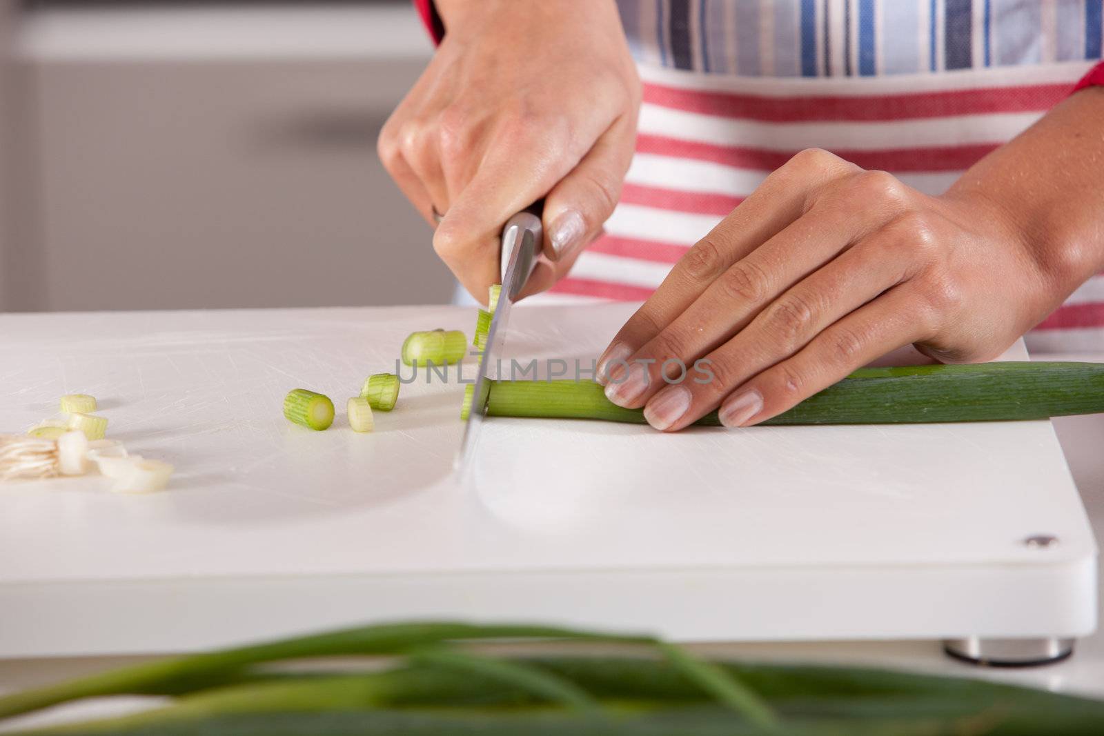 Woman hands cutting the spring onions with a big knife