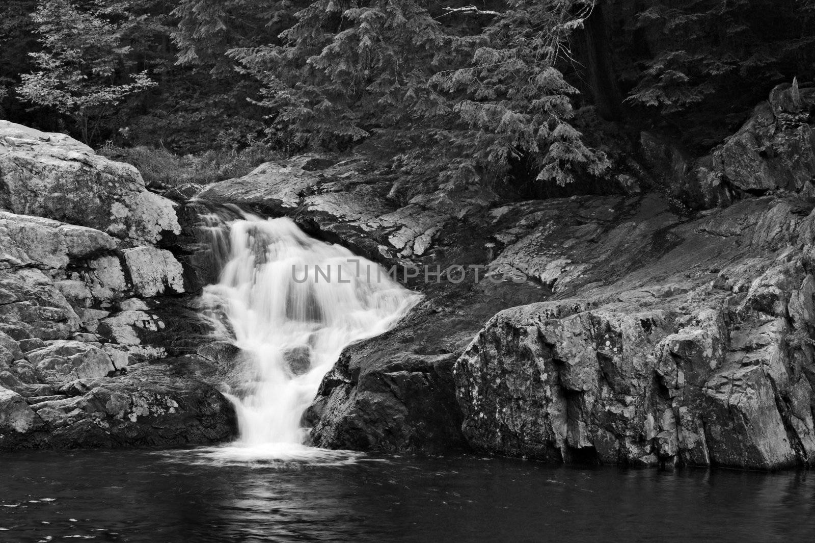 A waterfall surrounded by rocks and trees.