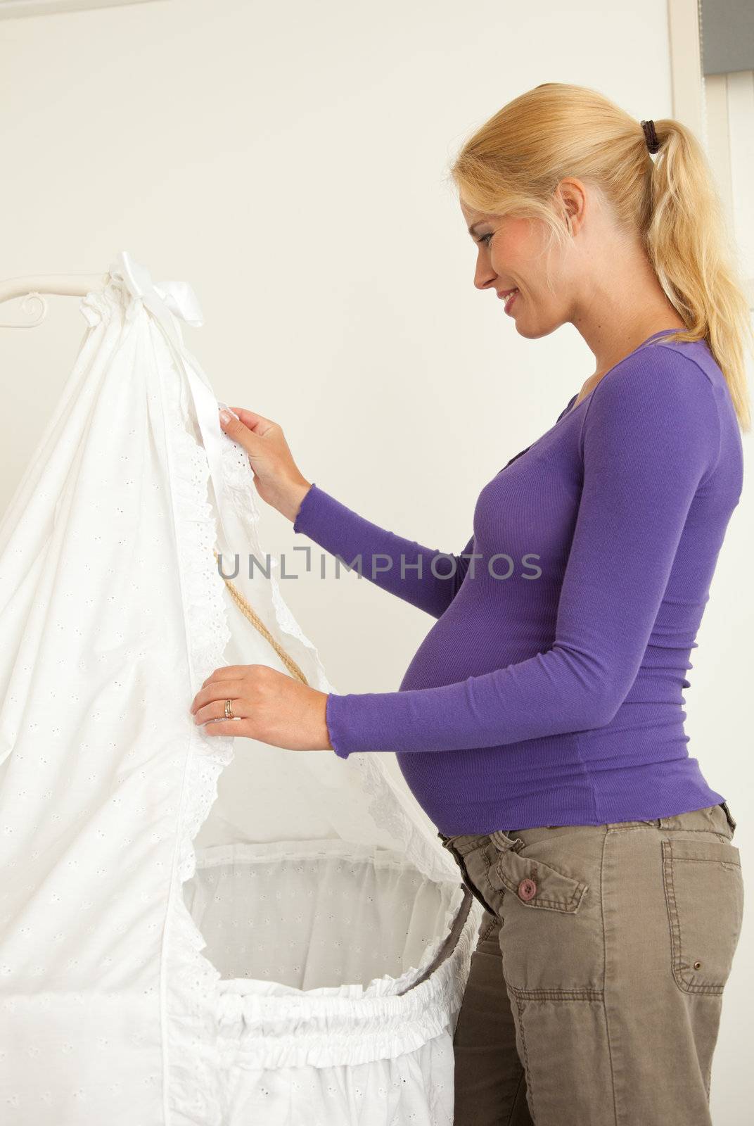 Mother arranging the curtains of the future crib for her baby