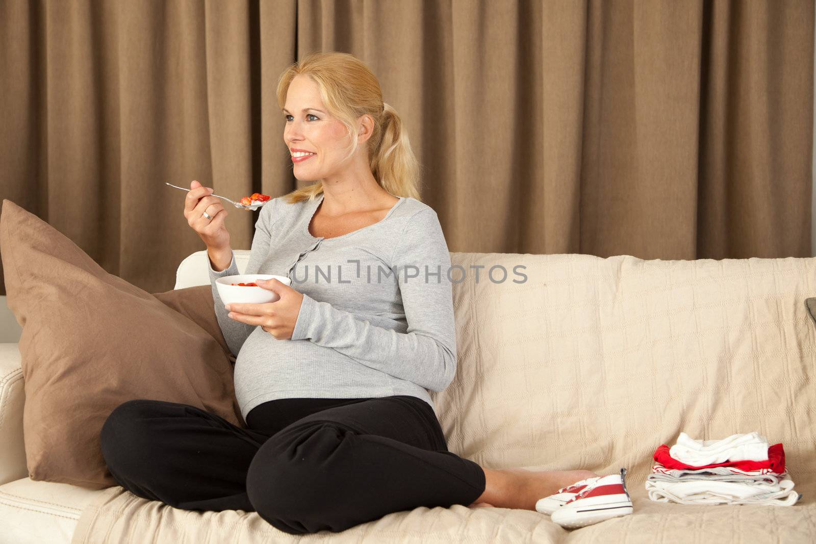 Beautiful pregnant woman looking happy and holding a bowl of healthy food